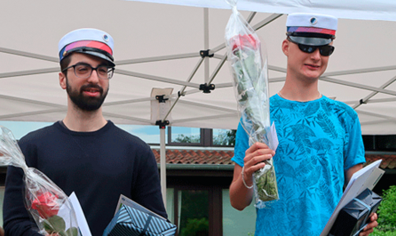 De to studenter står med huer og blomster