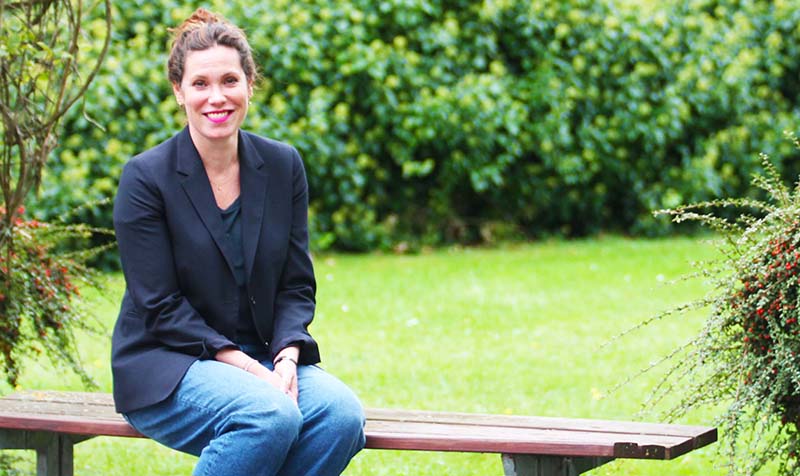 Marie Fasmer sidder på en bænk i IBOS have