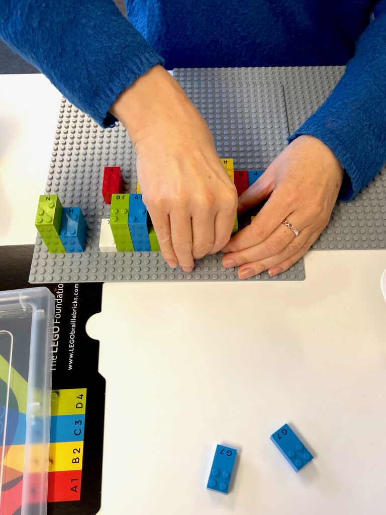 Hænder samler legoklodser