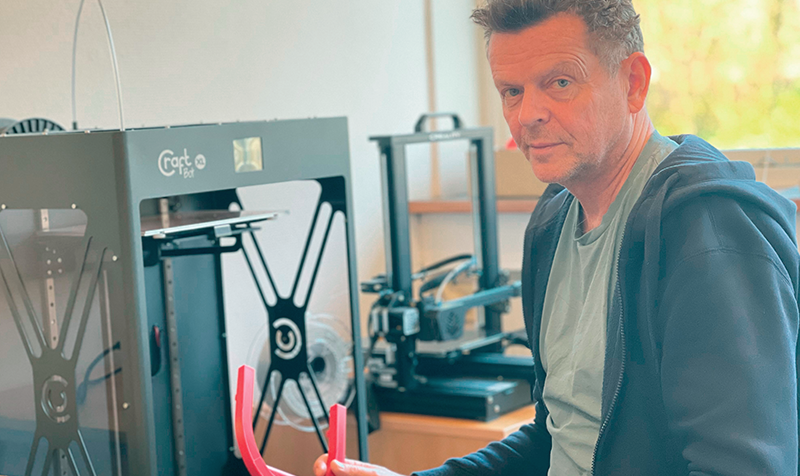 Underviser Jes sidder foran 3D-printer med kaffedims i hånden