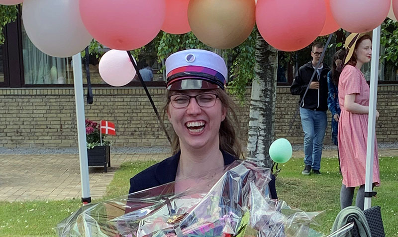 Foto af Anne Marie med STU-hue og blomster i favnen