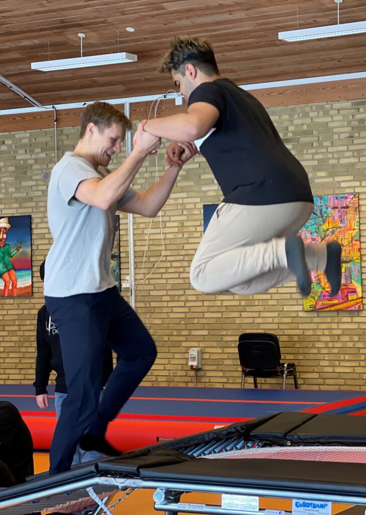 Instruktør støtter ung på trampolinen