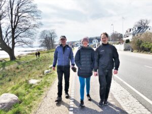 Tre personer går en tur tæt ved vandet