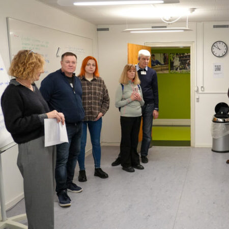 Tre ukrainske besøgende og en tolk står inden i et lokale og lytter til en IBOS-medarbejder.