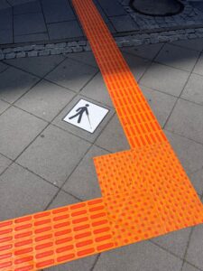 Foto af Navtac felter, der er sat fast på et fortorv. De har en meget kraftig orange farve.